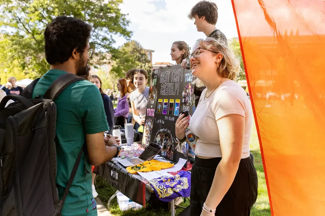 Students at table talking at involvement fair.